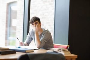 etudiant reflechissant avec livres et carnet ouvert